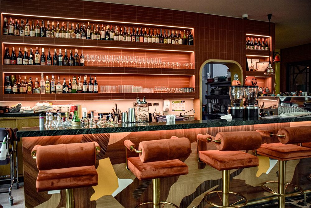Bar with velvet stools and backlit bottle shelves