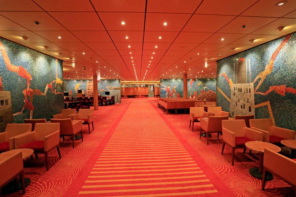 Colorful cruise ship lounge with mosaic murals and red seating