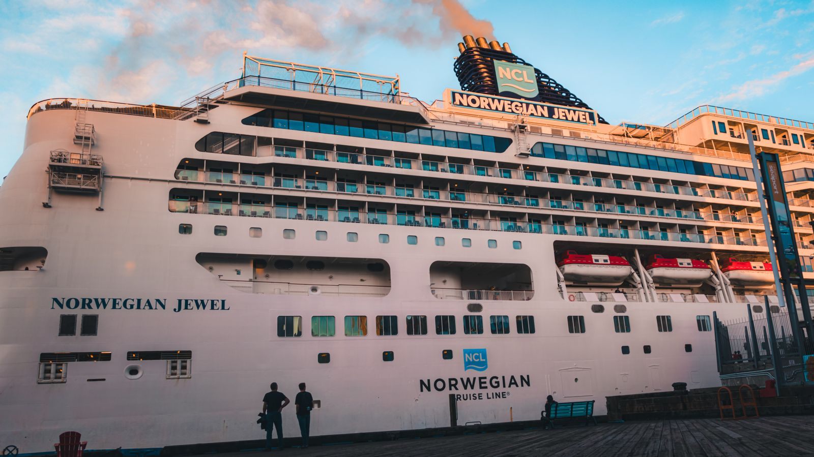 Norwegian Jewel cruise ship docked at sunset with passengers on the pier