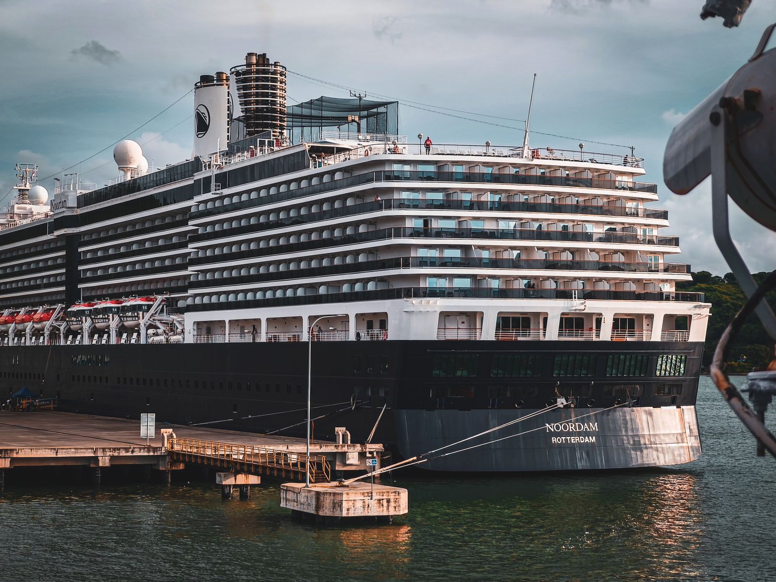 Holland America ship Noordam docked at a port under a dramatic sky